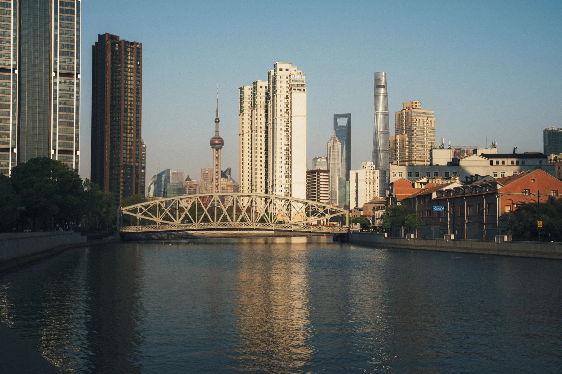 A steel bridge, brick warehouses and towers meeting along Suzhou Creek
