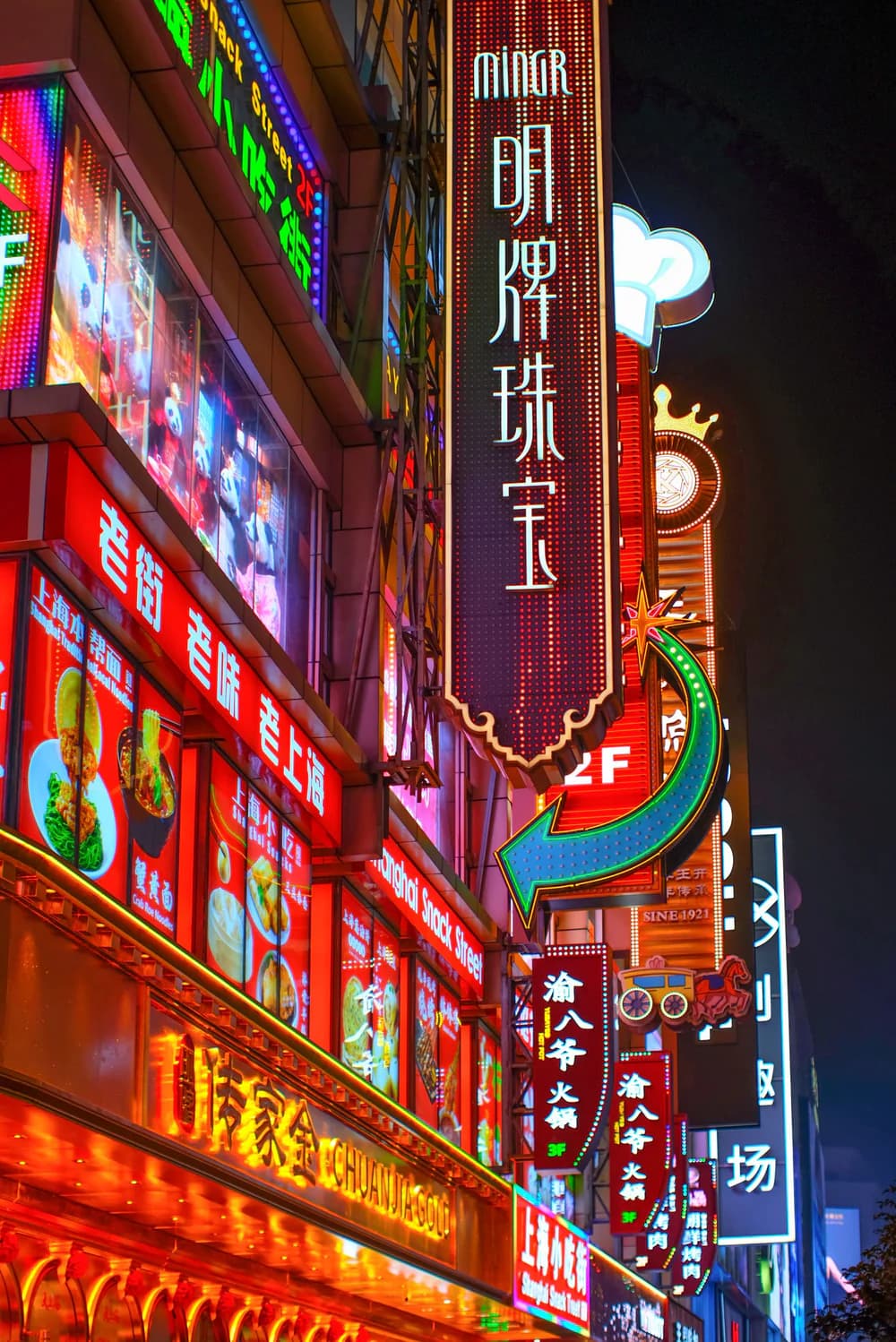 Layers of illuminated restaurant signs on a Shanghai street at night
