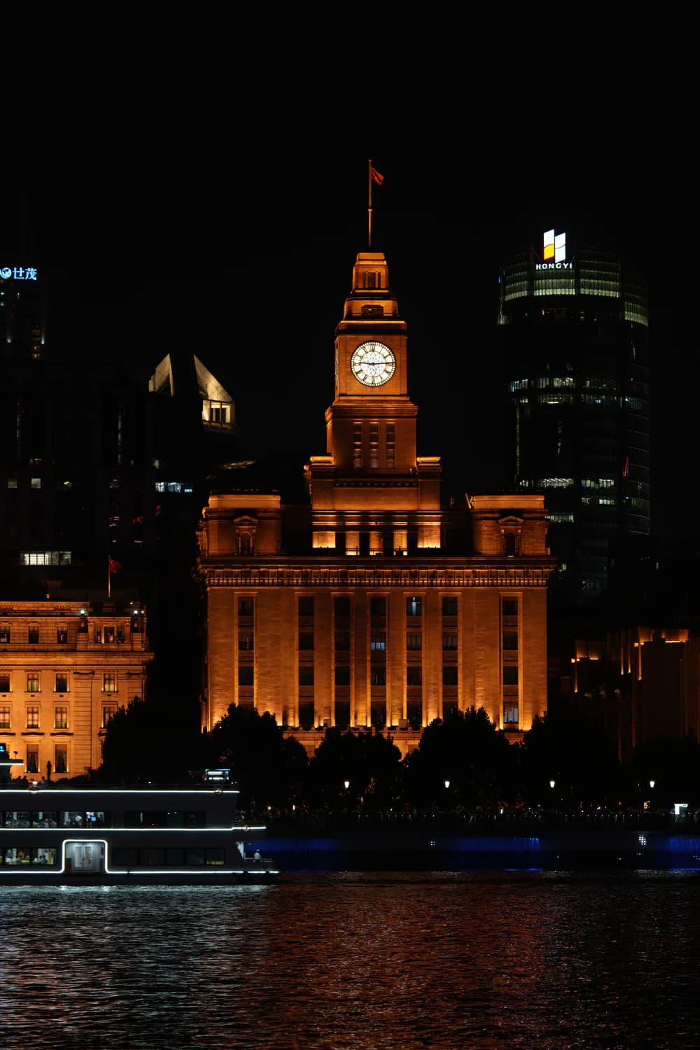 The illuminated Customs House clock tower beside the Huangpu River at night