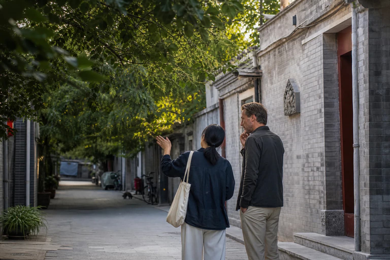 A traveler and local cultural interpreter walking and talking in a Beijing hutong