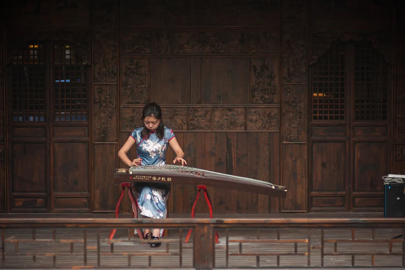 A musician playing the guzheng in a traditional interior