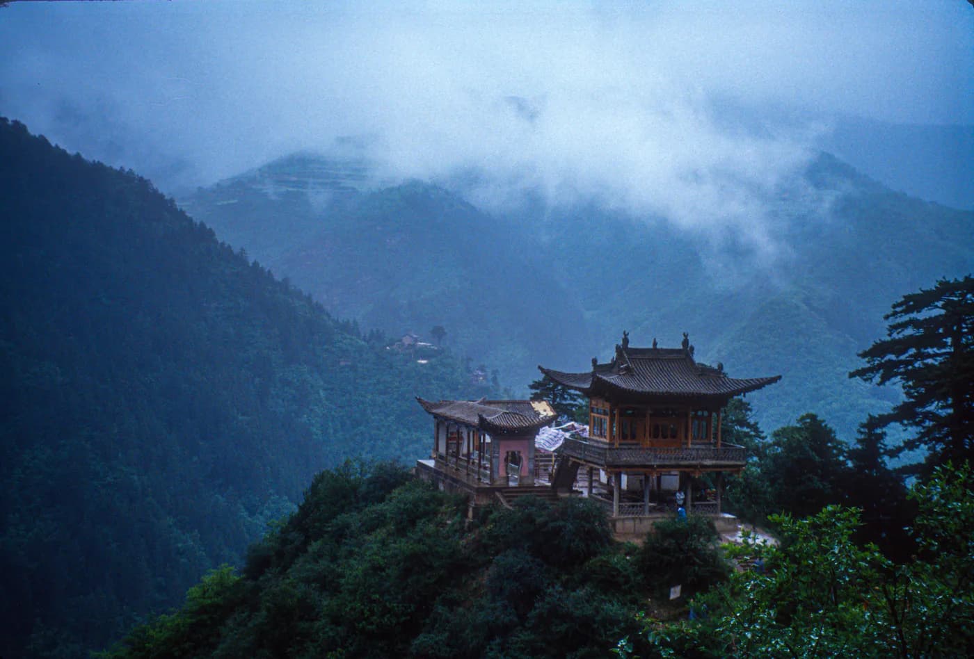 A mist-covered building set into the forested Wudang Mountains