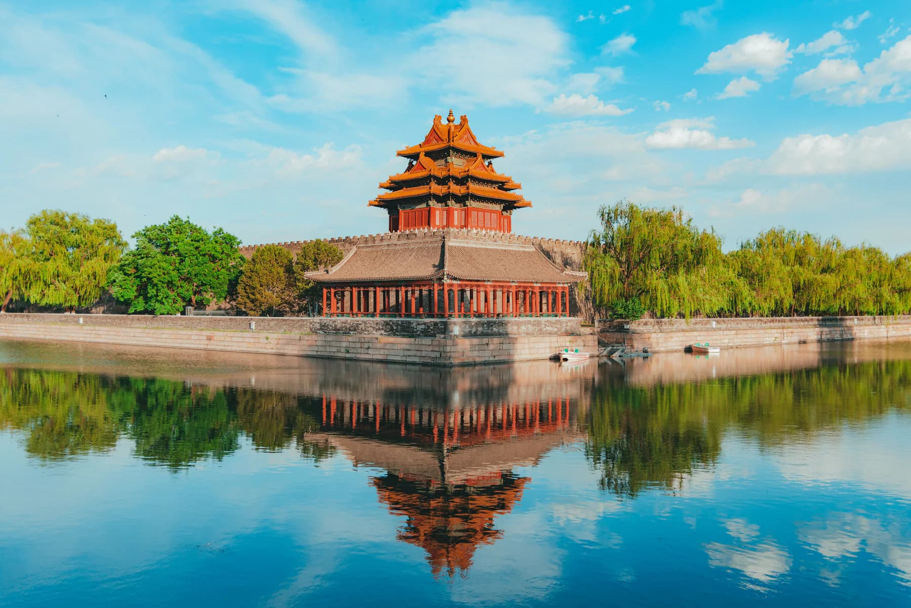 A historic Beijing corner tower reflected in its surrounding water