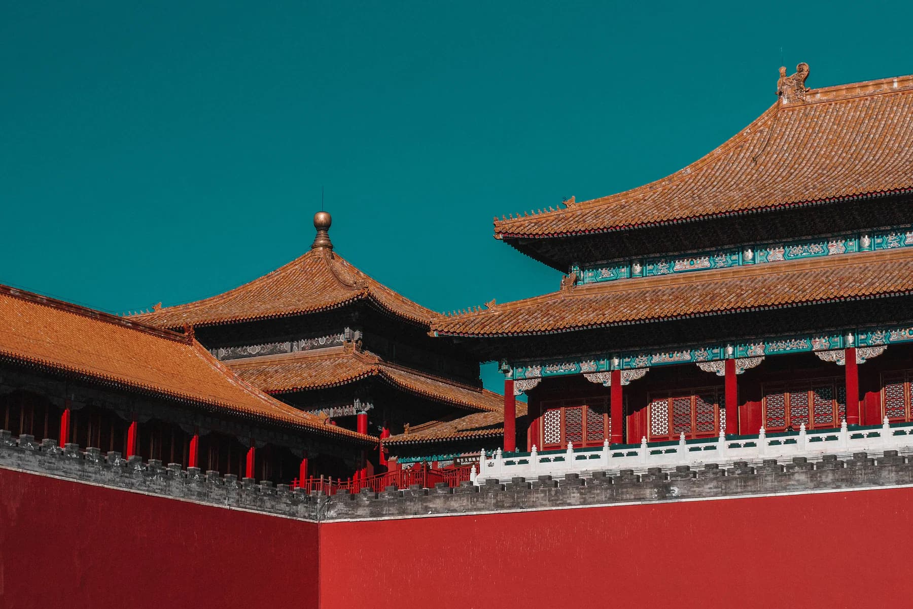 Traditional palace roofs and red walls beneath a clear Beijing sky