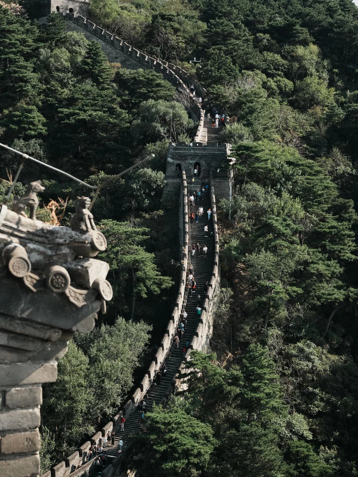 A steep section of the Great Wall climbing through green Beijing mountains