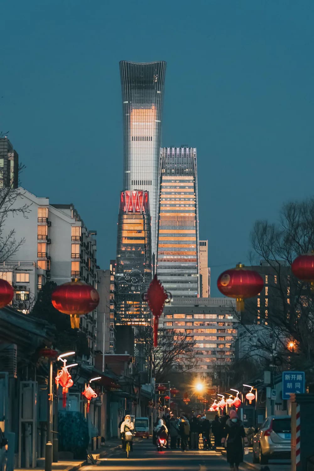 A contemporary Beijing street aligned toward a modern tower at dusk