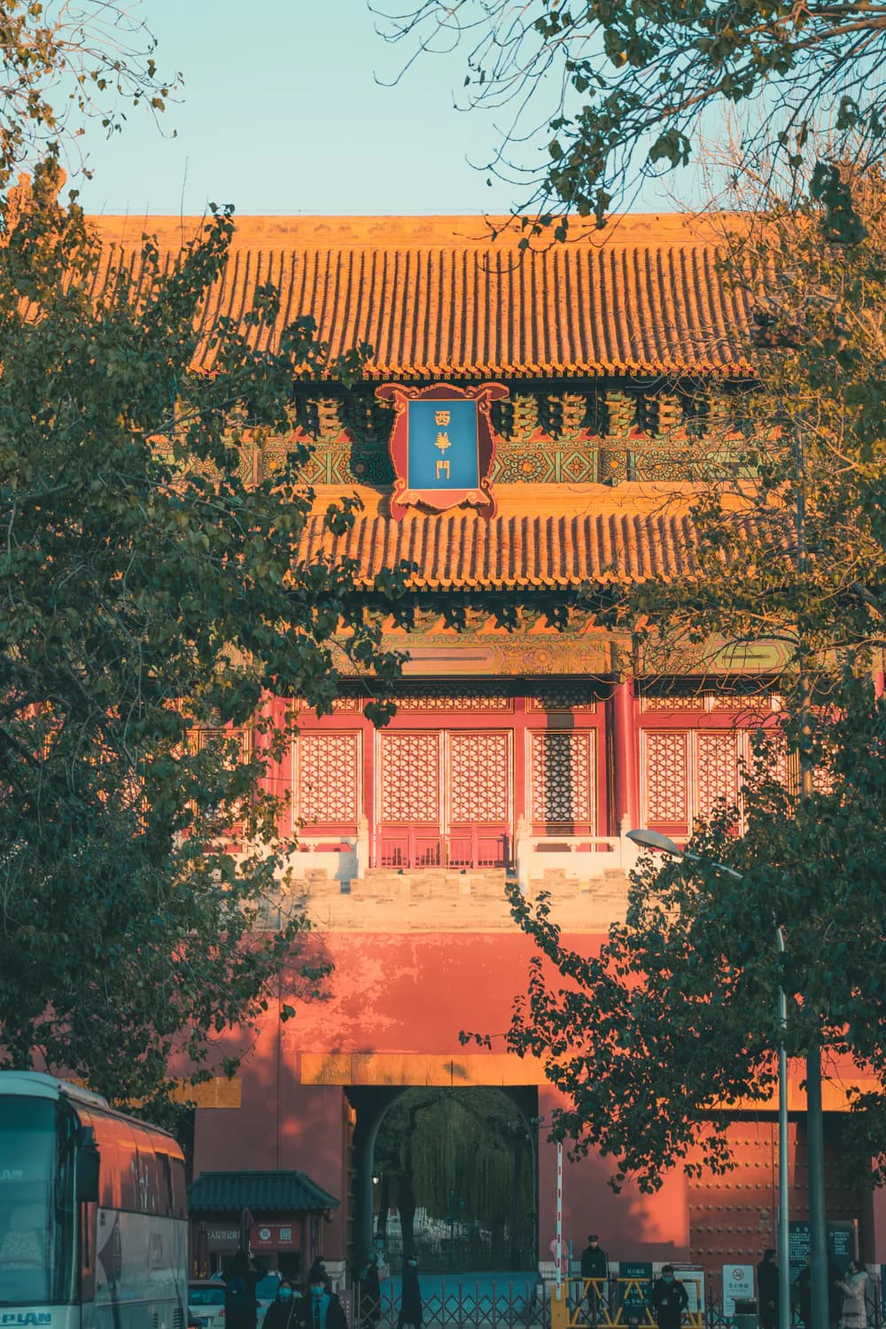 A red gate and traditional roof framed by Beijing trees
