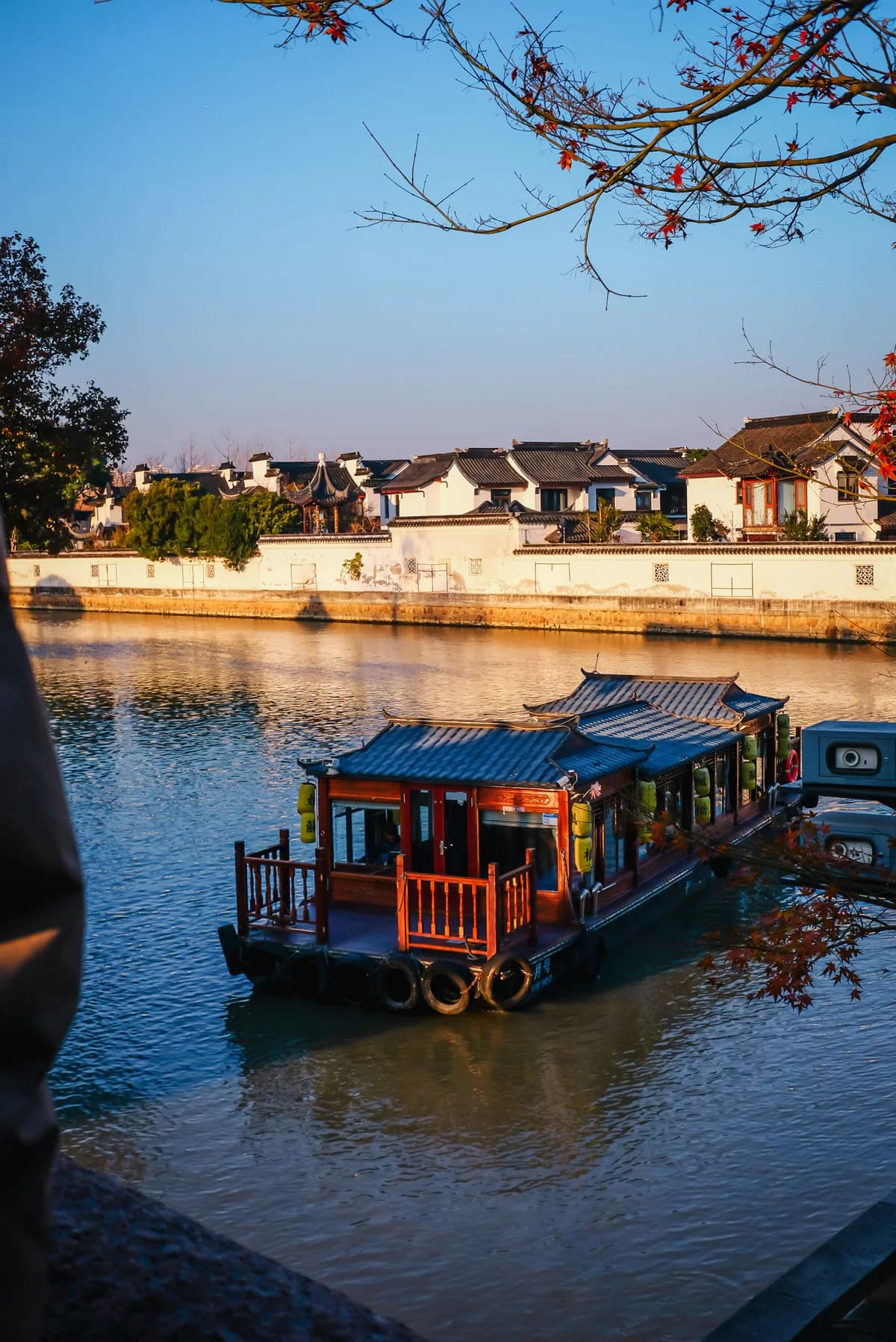 A boat passing whitewashed waterside houses along a Suzhou canal