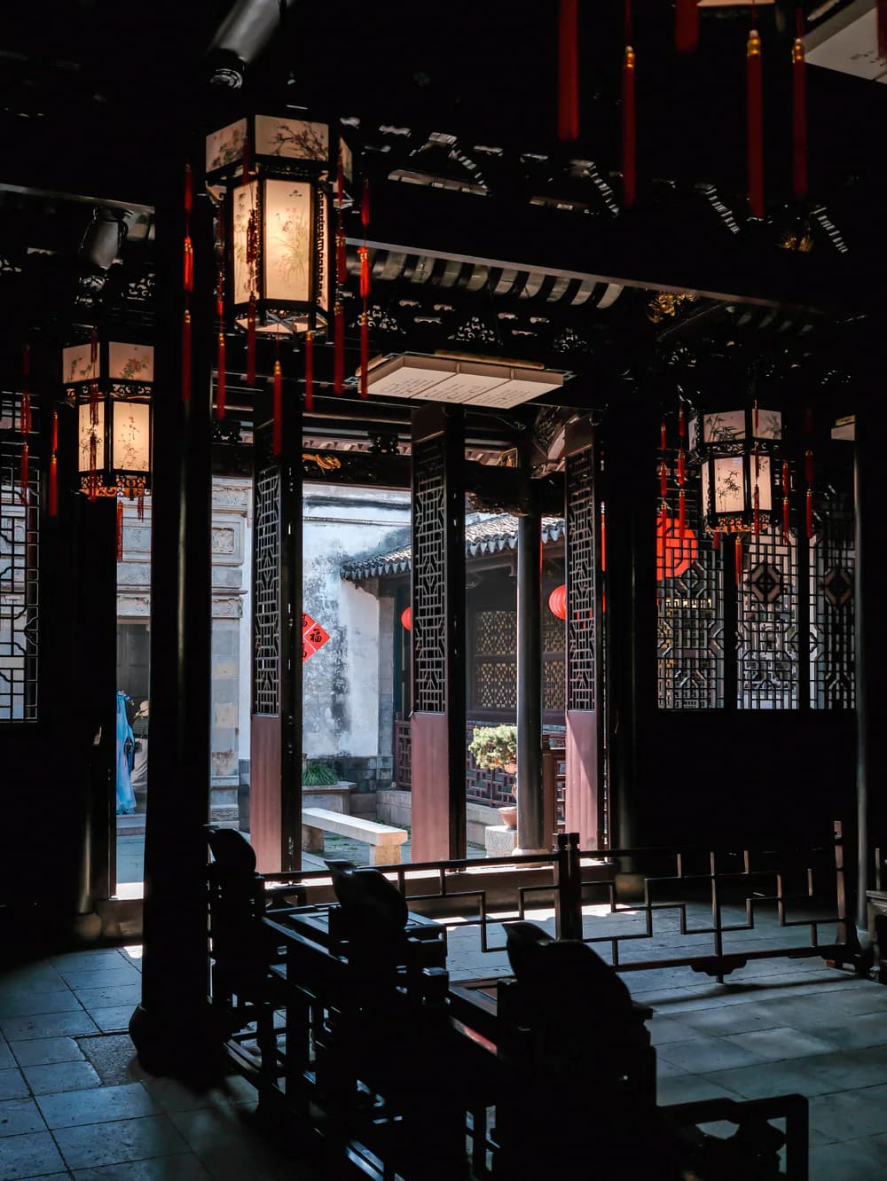 Lanterns and open doorways framing a quiet classical Suzhou interior
