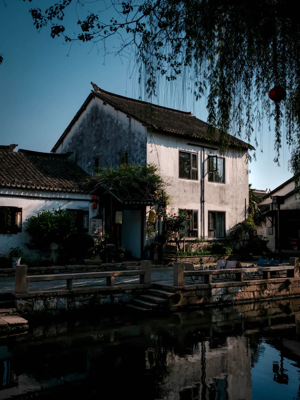 A willow and whitewashed house reflected in a Suzhou canal
