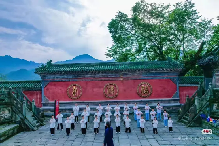 Young participants practising together beside a red temple wall